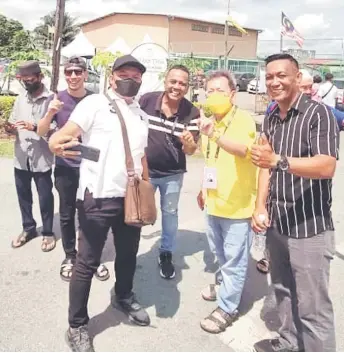  ?? ?? Dr Sim (front, second right) joining voters in a wefie during polling day last Saturday.