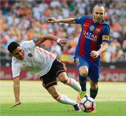  ??  ?? Going all out: Valencia’s Enzo Perez (left) vying for the ball with Barcelona’s Andres Iniesta in the La Liga match at the Mestalla on Saturday. Barcelona won 3-2.