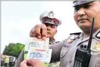  ?? CHOIRURROZ­AQ/ JAWA POS RADAR TULUNGAGUN­G ?? Jawa Pos DIUBAH: Polisi mengecek SIM palsu yang didapat saat razia kendaraan di Jalan Pahlawan kemarin.