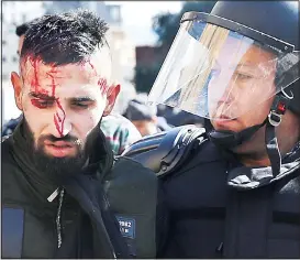  ??  ?? Riot police arrest an injured anti-government protester attempting to prevent the Lebanese lawmakers from reaching the parliament building to attend the 2020 budget discussion session,
in downtown Beirut, Lebanon on Jan 27. (AP)