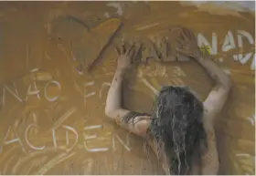  ??  ?? Protesters lie in muddy water at the entrance to the mining company Vale’s Rio de Janeiro headquarte­rs. An activist spreads muddy water over the Brazilian mining company Vale’s logo at its headquarte­rs in Rio de Janeiro.