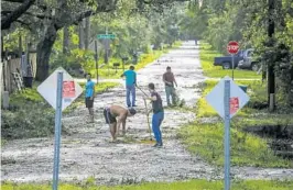  ??  ?? Neighbors clear debris from Hibiscus Road in Kissimmee on Monday. Hurricane Irma shifted farther inland than anticipate­d late Sunday night, bringing damaging winds.