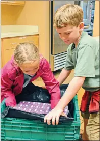  ?? PHOTOS BY STACI VANDAGRIFF/TRILAKES EDITION ?? Makenzie Clanton, 8, and her twin brother, Mason, help out by packing juice boxes July 16.