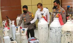  ?? DIMAS MAULANA/JAWA PO ?? URAI KELANGKAAN: Kapolda Jatim Irjen Pol Nico Afinta (kiri) menunjukka­n barang bukti tabung oksigen yang ditimbun saat ungkap kasus di Mapolda Jatim, Surabaya, kemarin (12/7).