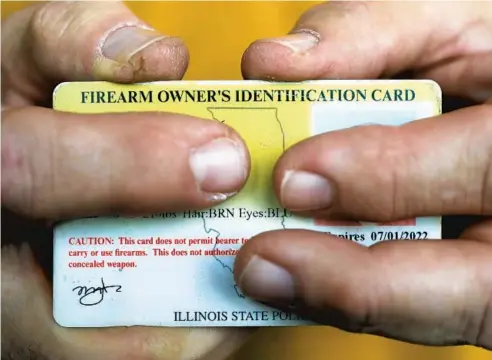  ?? JOHN J. KIM/CHICAGO TRIBUNE ?? A firearm owner’s identifica­tion card in 2019. The state requires the card for a resident to buy or possess a gun.