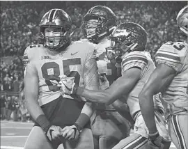  ?? Jamie Sabau Getty Images ?? MARCUS BAUGH celebrates with teammates after catching a 16-yard touchdown pass for the lead with 1:48 left in the fourth quarter against Penn State.