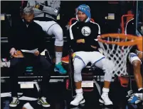  ??  ?? Warriors guard Stephen Curry, right, watches from the bench during the second half against the Nets on Tuesday in New York.