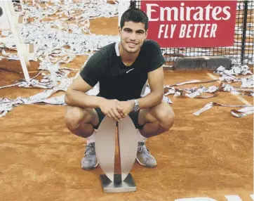  ?? ?? 0 Carlos Alcaraz poses with the Madrid Open trophy on the streamer-covered court