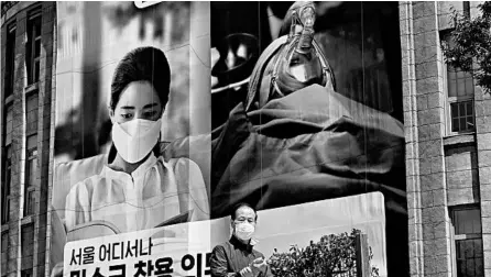  ?? JUNG YEON-JE/GETTY-AFP ?? A man walks past a banner advocating mandatory mask wearing in front of Seoul City Hall on Friday in Seoul, South Korea.