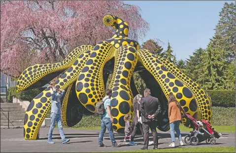  ??  ?? A family walks by one of Japanese artist Yayoi Kusama’s pumpkin sculptures at the New York Botanical Garden in New York. (AP/Mark Lennihan)