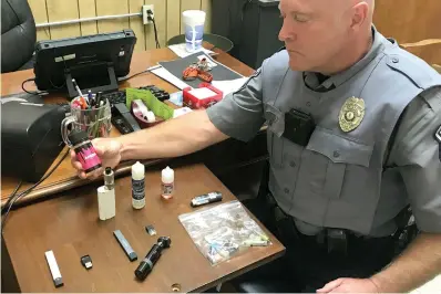  ?? Associated Press ?? ■ Bristol, Va., Police Officer Marlin Goff shows some of the vaping products he has confiscate­d from students at a high school. Congress is moving to pass the biggest new sales restrictio­ns on tobacco products in more than a decade, with support in 2019 from two unlikely backers: Marlboro-cigarette maker Altria and vaping giant Juul Labs.