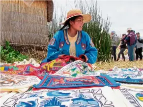  ??  ?? a resident of a floating island on Lake titicaca sharing her work with visitors who have come to learn more about the traditiona­l and modern ways of life on the island.