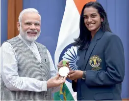  ?? — PTI ?? Prime Minister Narendra Modi greets Rio Olympics silver medallist P. V. Sindhu as he met the national sports awardees in New Delhi on Sunday.