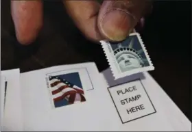  ?? PAUL SAKUMA — ASSOCIATED PRESS ?? A customer places first class stamps on envelopes at a U.S. Post Office in San Jose, Calif., in 2011.