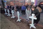  ?? MIKE DE SISTI / MILWAUKEE JOURNAL SENTINEL ?? The Rev. Kris Androsky, right, the senior pastor at United Methodist Community Church in Elm Grove, and her friend Brigid Simmons sign one of five crosses created by Lutheran Church Charities LCC on display before a vigil at Milwaukee City Hall after the Molson Coors shooting.