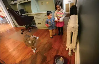  ??  ?? Aria Ricchetti helps teach her brother Leo how to feed their dog Zola prior to her leaving for school.