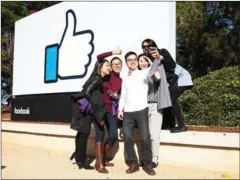  ?? LAURA MORTON/THE NEW YORK TIMES ?? Tourists from the Chinese University of Hong Kong take a selfie in front of a Facebook sign at the entrance to the company’s headquarte­rs in Menlo Park, California, last week.