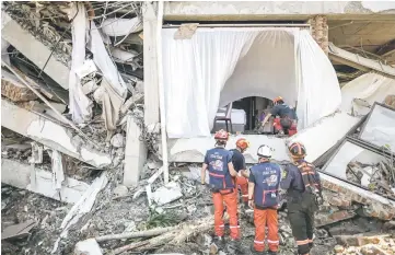  ?? — AFP photo ?? French members of the Internatio­nal Emergency Firefighte­rs prepare to enter the badly-damaged Mecure Hotel for search and rescue operations.