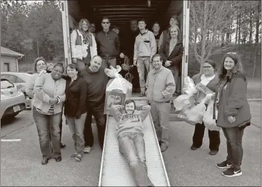  ?? Contribute­d photo ?? Leroy Peugh of Cherokee Logisitics (in sunglasses) and Tommy Britt (brown coat) help out DFCS by playing delivery drivers in the days ahead of Christmas by picking up gifts in Atlanta for local foster youth. When they got back to Polk County, they were helped by the Cedartown Honor Society and Future Business Leaders of America in unloading toys.