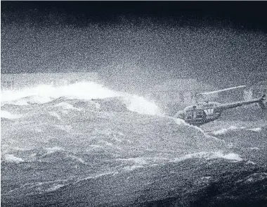  ??  ?? Helicopter hero: Peter Button of Capital Helicopter­s lowers his helicopter between the waves to pluck two police officers from the water after their launch, Lady Elizabeth II, sank at the Wellington Harbour heads.