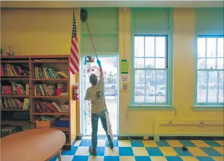  ?? Claire Hannah Collins Los Angeles Times ?? JORGE MUNOZ, an L.A. Unified worker, cleans the parent center at 49th Street Elementary in preparatio­n for the start of school.