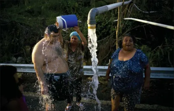  ?? RAMON ESPINOSA — THE ASSOCIATED PRESS ?? People affected by Hurricane Maria bathe in water piped from a mountain creek, in Utuado, Puerto Rico, on Oct. 14. Raw sewage is pouring into the rivers and reservoirs of Puerto Rico in the aftermath of Hurricane Maria. Puerto Ricans without running...