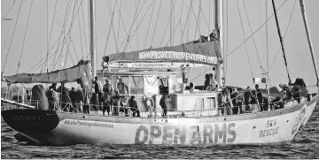  ?? — AFP photo ?? Migrants stand aboard Open Arms Astral board, of Spanish based non-government­al organisati­on Proactiva, some 24 nautical miles off Libya coast.