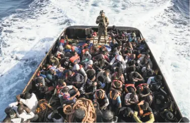  ?? Taha Jawashi / AFP / Getty Images ?? A Libyan coast guard officer watches over immigrants who were attempting to reach Europe last Tuesday.