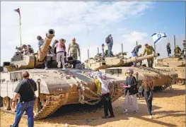  ?? Ohad Zwigenberg Associated Press ?? ISRAELIS stand on tanks at an event for families of reservists outside a military base in southern Israel. Talks to pause fighting in Gaza have gained momentum.