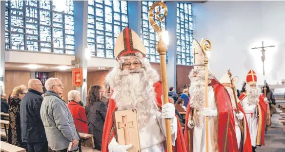  ?? FOTO: DPA ?? Sechs Mitglieder der Nikolausgi­lde ziehen aus der Kirche Friedrichs­hafen-Jettenhaus­en aus, um ihren ehrenamtli­chen Dienst an den Kindern zu verrichten: Die weltlichen Namen der Nikoläuse im Bild lauten (von links) Bertold Erich Schwarz, Hans Schultheiß, Werner Rießler und Erich Wölk.