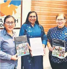  ?? ?? Noredah (left) showing the book which is presented by Dr Kler (centre). On the right is Cassie.