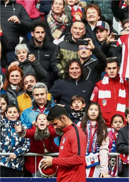  ?? — Reuters ?? Centre of attention: Atletico Madrid’s Diego Costa signing a ball as the fans cheer him on at the Wanda Metropolit­ano Stadium on Sunday.