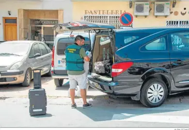  ?? ALBA FEIXAS ?? Un guardia civil recoge varios enseres después de investigar en el domicilio de los fallecidos.