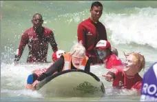  ?? RODGER BOSCH / AGENCE FRANCE-PRESSE ?? Pamela Hanford, 75, is helped by a team of coaches and volunteers to surf at an adaptive surfing event at Muizenberg beach, on January 20, in Cape Town, South Africa.