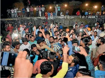  ?? AP ?? An angry crowd shouts slogans at the site where a speeding train ran into a crowd watching fireworks during a religious festival in northern India, killing at least 60 people.