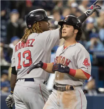  ?? AP PHOTO ?? COUNT IT: Hanley Ramirez celebrates as Andrew Benintendi scores on a basesclear­ing double in the 10th inning of the Sox’ win yesterday in Toronto.