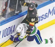  ?? JEFF VINNICK/GETTY IMAGES ?? Elias Pettersson of the Canucks takes a hit along the boards from Vegas’ Alex Tuch during Game 1 on Sunday.