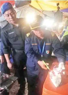  ??  ?? Officers showing one of the 110kg of bombed fish that were seized behind the Handicraft Market.