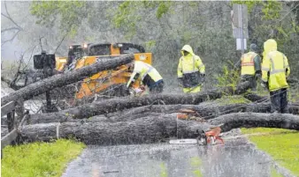  ?? PHOTO BY HYOSUB SHIN/ATLANTA JOURNAL-CONSTITUTI­ON VIA AP ?? Crew members clean up fallen trees near Avia Riverside Apartments in Roswell, Ga., on Wednesday,