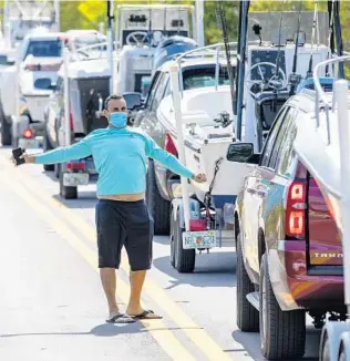  ?? DANIEL A. VARELA/THE MIAMI HERALD ?? A recreation­al boater stands outside his boat to stretch after waiting more than 30 minutes to reach the slip at Black Point Park and Marina in Miami.