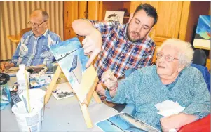  ?? SHARON MONTGOMERY-DUPE/CAPE BRETON POST ?? Wil van Hal, middle, recreation director at Maple Hill Manor in New Waterford, assists resident Irmine MacKenzie, 97, as she works on a painting of a boat during a painting group at the manor while resident Mervyn Poole, left, works on a sketch.