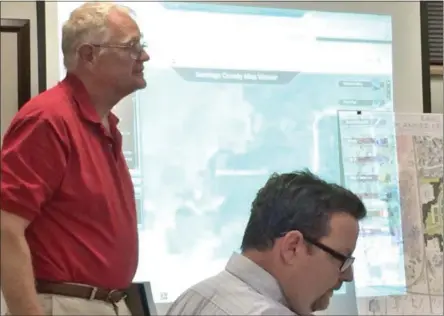  ?? GLENN GRIFFITH - GGRIFFITH@DIGITALFIR­STMEDIA.COM ?? Clifton Park resident Jim Ruhl, standing left, shares his vision for the area surroundin­g the Park West condo project with the Planning Board at a recent meeting. Seat on right is town Planning Director John Scavo.