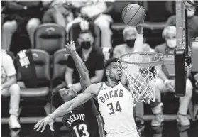  ?? Lynne Sladky / Associated Press ?? Bucks forward Giannis Antetokoun­mpo shoots as Heat center Bam Adebayo defends. Antetokoun­mpo finished with 20 points, 12 rebounds and 15 assists.