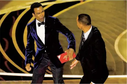  ?? CHRIS PIZZELLO APPHOTOS ?? Presenter Chris Rock grimaces after being hit onstage by actor Will Smith while presenting the Oscar for best documentar­y last Sunday.