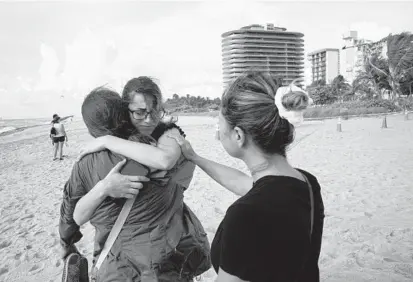  ?? LYNNE SLADKY/AP ?? Faydah Bushnaq, center, of Sterling, Va., hugs Maria Fernanda Martinez, of Boca Raton, Fla., on Friday near the 12-story condo tower that collapsed early Thursday morning in Surfside, Florida. The cause of the collapse is not yet known.