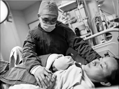  ?? QINHUAI / VISUAL CHINA ?? A mother holds her newborn baby girl as her husband comforts her at Nanjing Maternity and Infant Hospital on Monday.