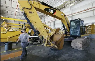  ?? ROGELIO V. SOLIS — THE ASSOCIATED PRESS ?? A Puckett Machinery Co. technician walks past a new heavy-duty Caterpilla­r excavator that awaits modificati­on at Puckett Machinery in Flowood, Miss. Caterpilla­r continued to see a healthy surge in sales during its fourth quarter of 2022, as the economy strengthen­s.