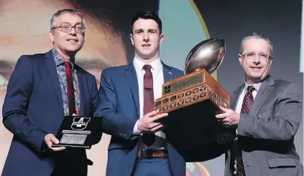  ?? THE CANADIAN PRESS ?? Calgary Dinos quarterbac­k Adam Sinagra receives the Hec Crighton Trophy as the most outstandin­g player in Canadian university football from Vanier Cup organizer Christian Cote and Sylvain Fauchon of Promutuel, left, at the U Sports football gala in Quebec City on Thursday.