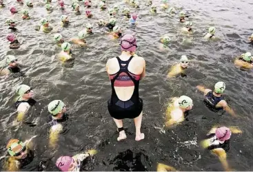  ?? Brett Coomer / Houston Chronicle ?? Competitor­s start the Memorial Hermann Ironman Texas triathlon Saturday with a splash, entering Lake Woodlands for a 2.4-mile swim on the first leg of an event that includes a 112-mile bike ride and 26.2-mile run.