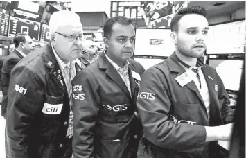  ?? ASSOCIATED PRESS ?? Trader Thomas Ferrigno, left, works with specialist­s Dilip Patel, center, and Karan Virdi on the floor of the New York Stock Exchange.